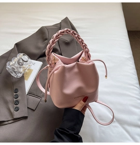 Detailed view of pink lychee textured bucket bag with woven handle on white bedding background