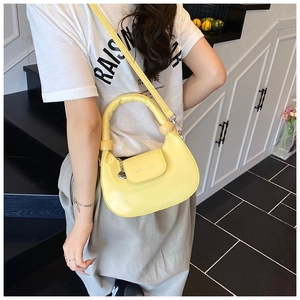 Bright yellow crescent moon bag with thick handle shown on model in a casual setting