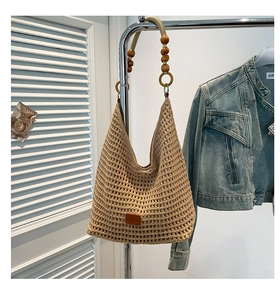 Detail of hand-woven hollow mesh tote bag featuring wooden bead handles and leather patch