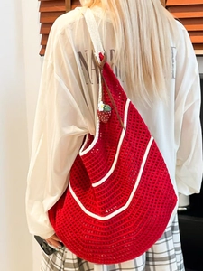 Handmade red crochet shoulder bag with white trim and strawberry pendant on a model