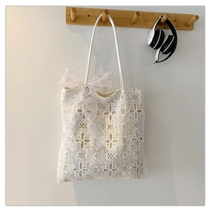 Dettaglio della borsa tote in pizzo bianco con nastro di seta a fiori rosa decorativo