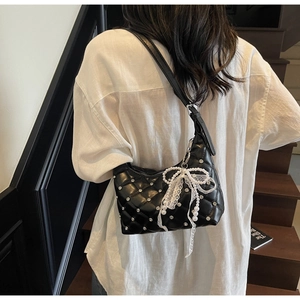 Detail of black quilted shoulder bag featuring silver rhinestones and lace pearl charms