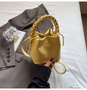 Detail of yellow lychee leather bucket bag with braided handle and drawstring closure