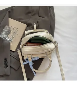 Detailansicht der cremefarbenen Vintage-Tasche mit blau karierter Schleife und Reißverschluss
