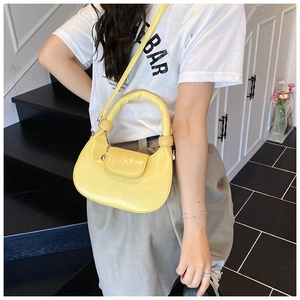 Detailed view of yellow crescent shoulder bag with glossy PU leather and magnetic closure