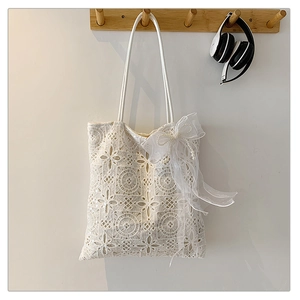 Dettaglio della borsa tote in pizzo bianco con ricami floreali e elegante fiocco in organza