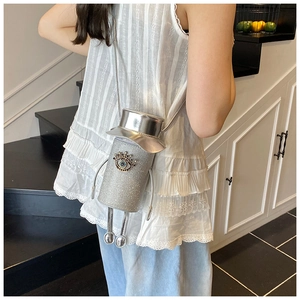 Detail showing creative silver cylinder crossbody bag with glittering devil eye and hat design