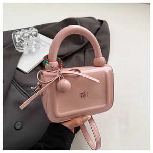 Dettaglio della borsa a mano rosa lucida con fiocco decorativo e ciondolo a sfera