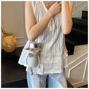 Detailed view of robot-shaped mini crossbody bag with silver sequins and demon eye charm