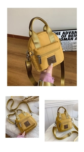 Detailed macro view of yellow nylon crossbody bag with adjustable strap and front zipper