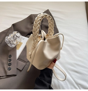 Detail of off-white bucket bag with woven handle and drawstring on casual blazer