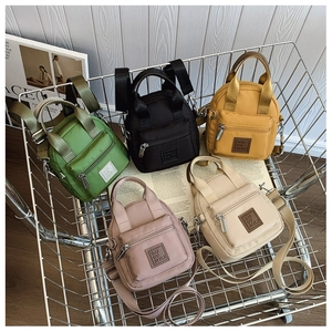 Mini nylon crossbody bags in five colors displayed in a metal basket on white background