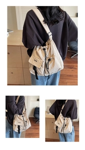 Detail view of large cream nylon bucket bag with drawstring closure and side flap pocket