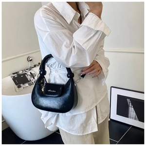 Detail of black crescent shoulder bag with knotted handle and silver metal hardware accents