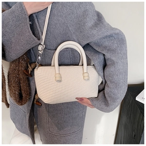 Detailed macro view of white textured mini handbag with silver metal hardware and straps