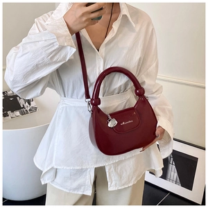 Detail view of burgundy glossy crescent bag with round handle and silver lock decoration