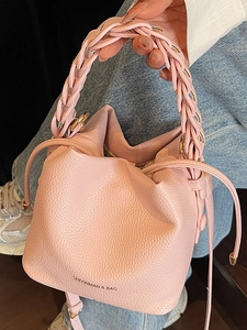 Chic pink lychee leather bucket bag with woven handle and drawstring closure for women