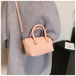 Detail showing the light pink square bag with woven texture and decorative knot handle details