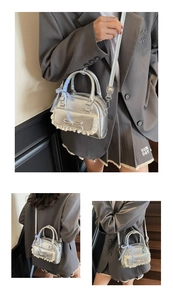 Detailansicht der silbernen Handtasche mit Spitzenbesatz und blauer Karo-Schleife