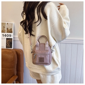 Nylon crossbody bag in lotus pink shown on model with shoulder strap and front zipper
