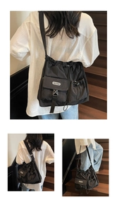 Detail of black nylon cargo crossbody bag featuring drawstring closure and multiple pockets