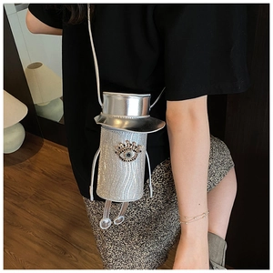 Detail of silver crossbody bag with sequined eye design and top hat lid style