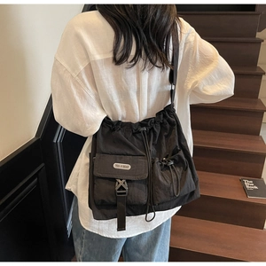 Detailed back view of a large black nylon drawstring crossbody bag on a model