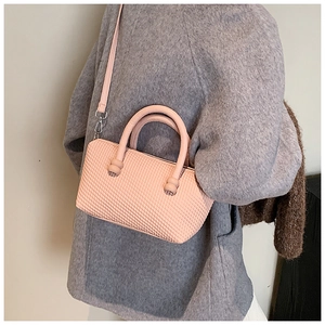 Detail of light pink crossbody bag with woven texture and adjustable shoulder strap