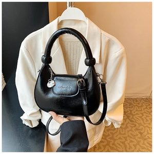 Detail of black crescent handbag with knotted handle and silver G-letter charm accent