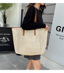 Detail of woven straw tote bag with brown leather straps and spacious interior for summer