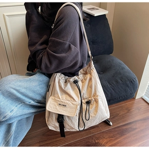Detail of off-white drawstring crossbody bag featuring large capacity and front buckle pocket