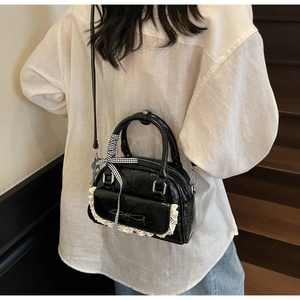 Detailansicht der schwarzen Lackleder-Bowlingtasche mit weißer Spitze und Schleife