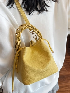 Chic yellow lychee leather bucket bag with woven handle and drawstring closure for women