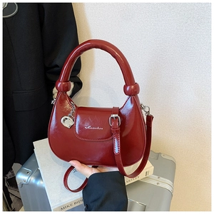 Macro shot of red patent leather moon bag with metallic G pendant and chunky round handle
