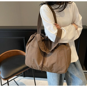 Detailed view of brown nylon tote bag with drawstring closure and large front pocket