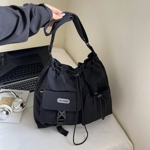 Detail view of black nylon messenger bag with drawstring closure and buckle pocket