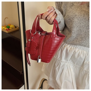 Detailed macro view of red crocodile pattern bucket bag with silver padlock and charm
