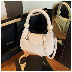 Detail view of cream crescent leather bag with chunky handle and branded logo engraving