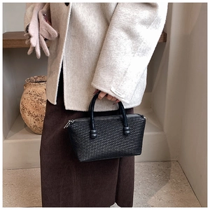 Détail du sac à main noir tressé avec texture de luxe, doubles poignées et fermeture éclair