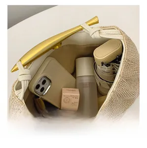 Spacious interior of a straw handbag showing capacity for phone, umbrella and cosmetics