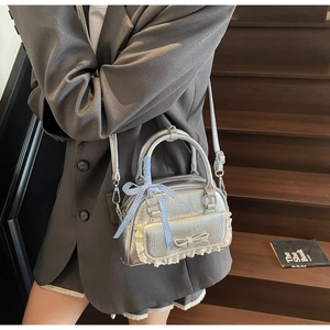 Detail der silbernen Metallic-Tasche mit Spitze und blau kariertem Band am Griff