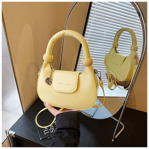 Detailed view of yellow half-moon bag with wooden bead handle and silver metal charm