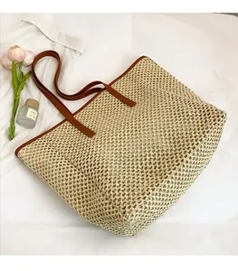 Detail of woven straw tote bag featuring brown leather buckle and handles on white background