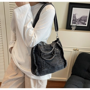 Close-up of charcoal denim bag featuring vintage wash texture and silver metal rivets