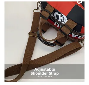 Détail de la bandoulière réglable avec crochet en bronze sur un sac rouge et noir