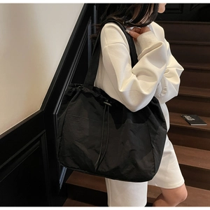 Detail of black waterproof nylon tote bag with drawstring closure and pleated texture
