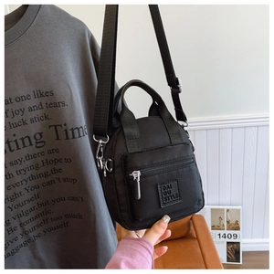 Detailed view of black nylon crossbody bag with zipper pocket and logo strap