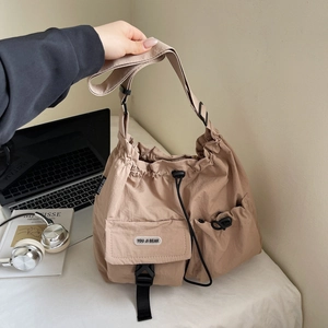 Detail of khaki nylon crossbody bag showing drawstring closure and buckled front pocket