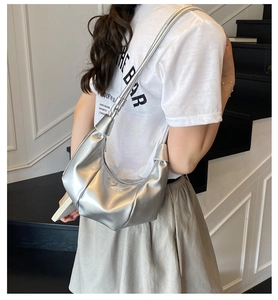 Detailed view of metallic silver dumpling bag with stylish pleated texture and adjustable strap