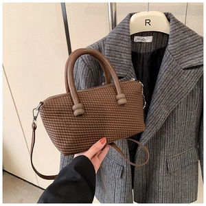 Detail of dark brown woven texture handbag showing high-quality synthetic leather material